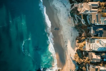 Aerial view of a Mexican coastline with beachfront homes, comparing buying property in Mexico vs the US and Canada