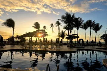 Golden sunset over a resort pool with palm trees, evoking a Mexican timeshare resort