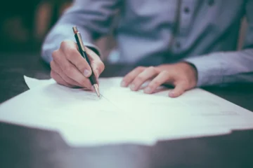 A person signing a real estate document, illustrating the notary and lawyer roles when buying property in Mexico