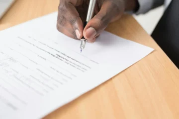 A person signing an official document, representing the notario's role in Mexican property transactions